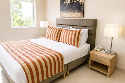 a bedroom with a bed with an orange and white striped blanket at Hotel Neiva Plaza in Neiva