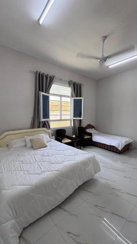 a white bedroom with a large bed and a window at Jabal Shams, Al Noor house جبل شمس in Misfāh