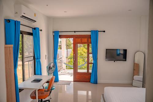 a bedroom with blue curtains and a desk and a door at Modern Nature Retreat in Ko Phangan