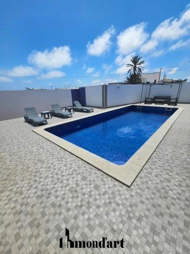 a swimming pool with chairs next to a building at Sablette mostaganem in Les Sablettes Mazagran-Plage