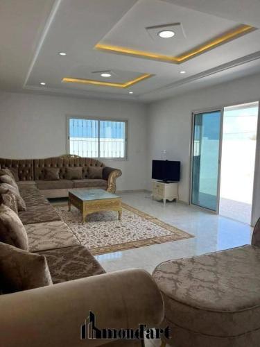 a living room with couches and a table and a tv at Sablette mostaganem in Les Sablettes Mazagran-Plage