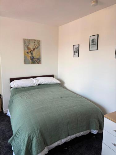 a bedroom with a green bed with two pictures on the wall at Sunny and Comfortable Studio in Southport