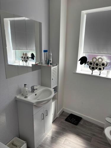 a white bathroom with a sink and a mirror at Sunny and Comfortable Studio in Southport
