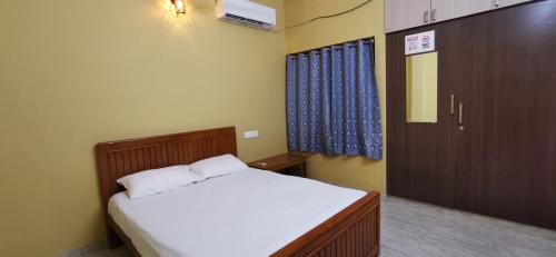 a small bedroom with a bed and a cabinet at Carmel Stay in Madurai