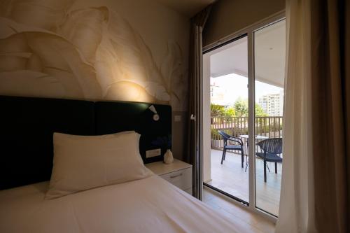 a bedroom with a bed and a balcony with a table at Otti Hotel in Vlorë
