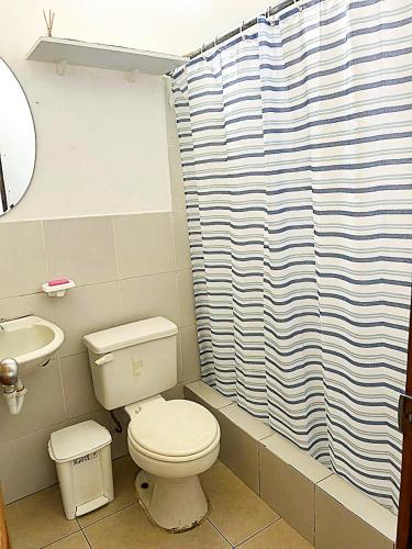 a bathroom with a toilet and a shower curtain at Caracola, habitación privada de Flor de Lis Beach House in Playas