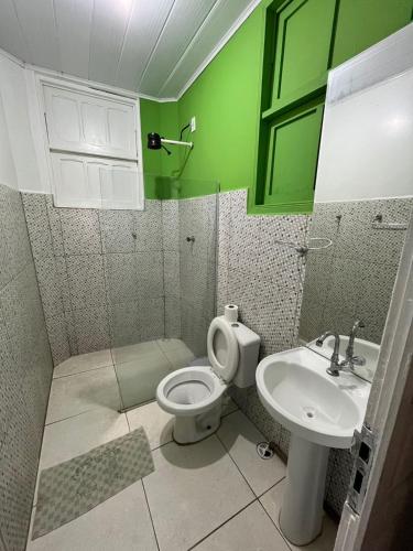a green bathroom with a toilet and a sink at Pajuçara Inn - Pousada Maceió in Maceió