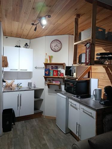 a kitchen with white cabinets and a black counter top at Résidence le Schuss Studio Montagne en bas des pistes in Vars
