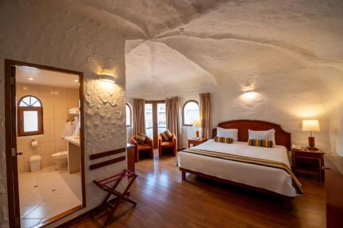 a bedroom with a large bed and a bathroom at San Agustin Internacional in Cusco