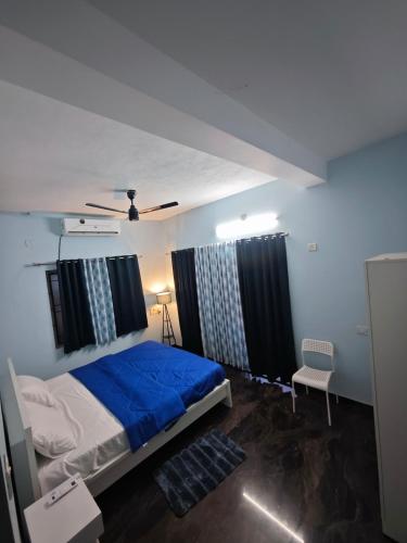 a bedroom with a bed with blue sheets and curtains at The Reset House Mangalore in Mangalore