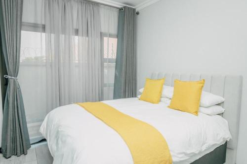 a bedroom with a bed with yellow pillows and a window at Beck Apartments - Kitwe in Kitwe