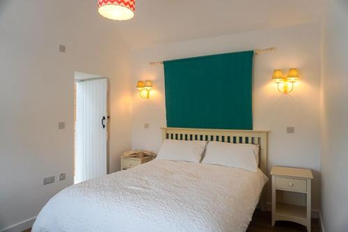 a bedroom with a white bed and a green wall at Bron Haul in Newborough