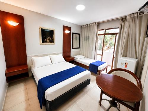 a bedroom with a bed and a desk and a table at Hotel Alvorada Taguatinga by Bsb Inn in Taguatinga