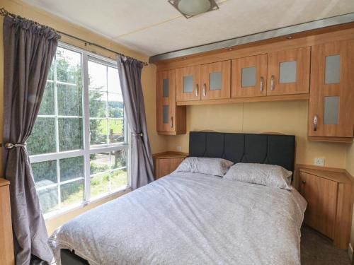 a bedroom with a bed and a large window at Hawks View Caravan in Macclesfield