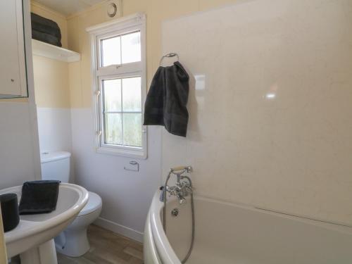 a bathroom with a tub and a toilet and a sink at Hawks View Caravan in Macclesfield