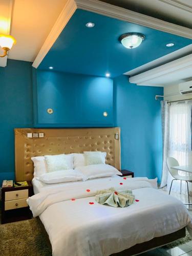 a bedroom with a large bed with blue walls at Hotel Omnisport in Limbe