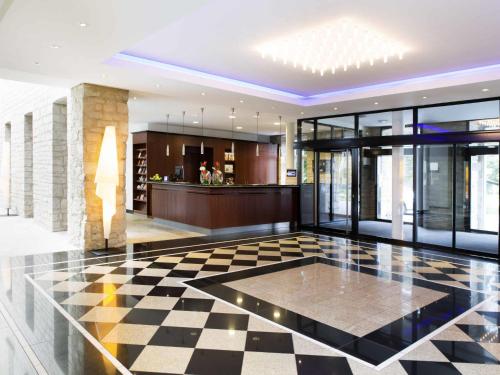 eine Lobby mit Schachbrettmusterboden und einer Bar in der Unterkunft NOVOTEL Hildesheim City in Hildesheim