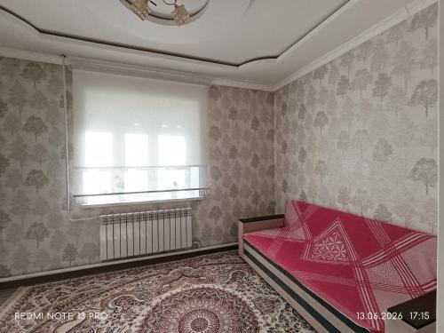a bedroom with a red bed and a window at Baktygul in Karakol