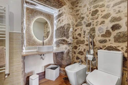 a stone walled bathroom with a toilet and a sink at Casa do Forno in Ponte da Barca