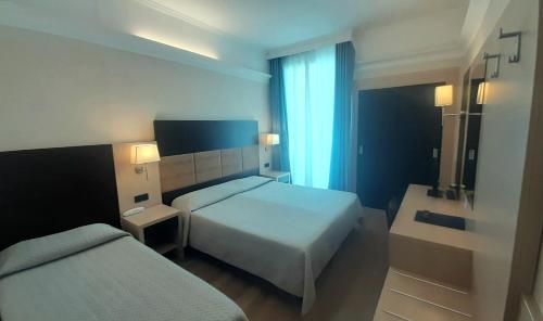 a hotel room with two beds and a window at Hotel Enrichetta in Desenzano del Garda