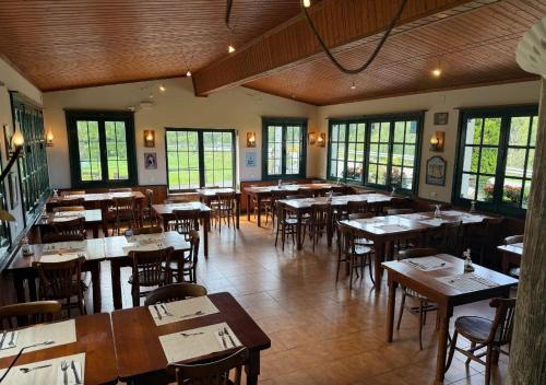 a dining room with tables and chairs and windows at Aldea del Trasgu in Cuerres