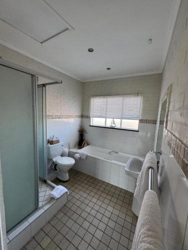 a bathroom with a tub and a toilet and a sink at Eagles Rest Guest House in Summerstrand