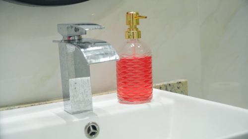 a bottle of red liquid sitting next to a faucet at Quarto Aconchegante Teresópolis Refúgio Cristão in Teresópolis