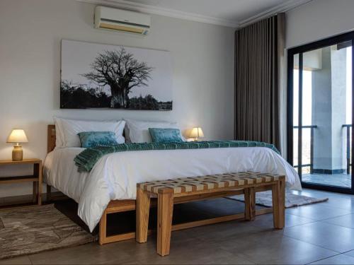 a bedroom with a large bed with a tree on the wall at Thaba Tshwene Game Lodge in Hartbeesfontein