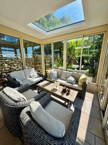 a living room with couches and tables and windows at Le Coin Tranquille in La Roque-Gageac