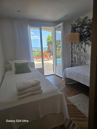a white bedroom with a bed and a sliding glass door at La lézarde in Cavalaire-sur-Mer