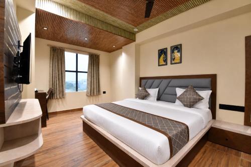 a bedroom with a large bed and a flat screen tv at Luxora Suites in Jaipur