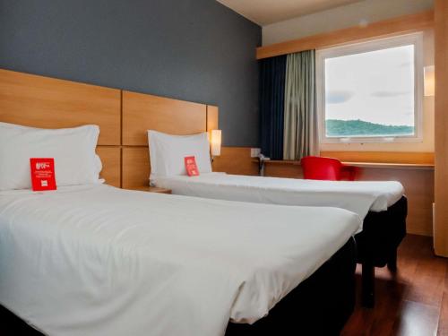 a hotel room with two beds and a window at ibis Joinville in Joinville