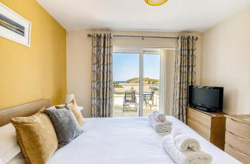 a bedroom with a bed with a tv and a balcony at The Beach House & Porth Sands Apartments in Newquay