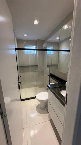 a bathroom with a toilet and a glass shower at Flat Eufrates 205 in Olinda