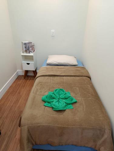 a bed with a green flower on top of it at Quarto Aconchegante Teresópolis Refúgio Cristão in Teresópolis