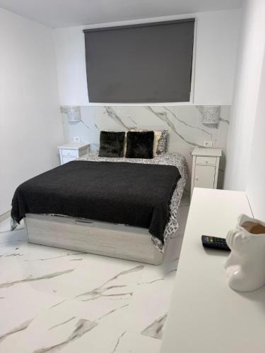 a white bedroom with a bed with a black blanket at Cura Marina 2 in Playa del Cura