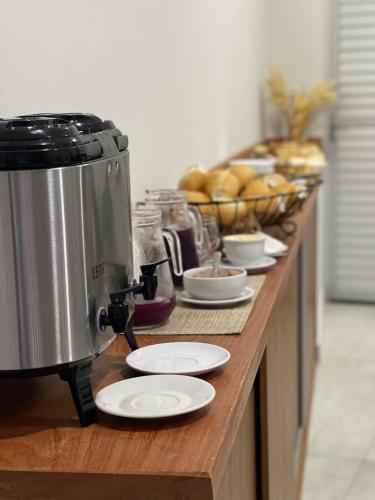 a counter with plates and a food processor on it at Neves Hotel II in Ipatinga