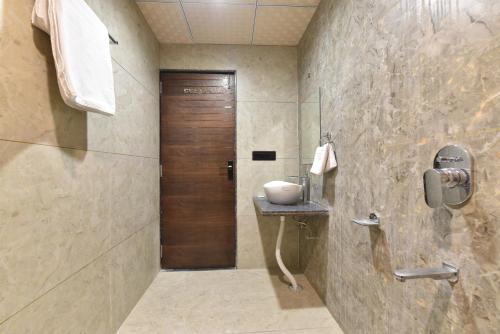 a bathroom with a sink and a wooden door at Luxora Suites in Jaipur