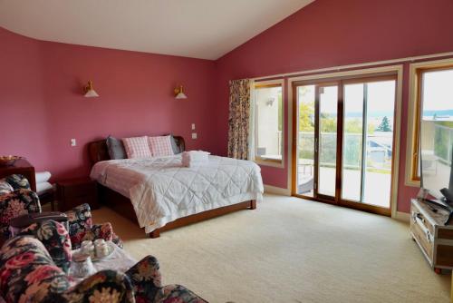 a bedroom with red walls and a bed and a balcony at The Shearwater House - Panoramic Ocean View Suites in Nanaimo