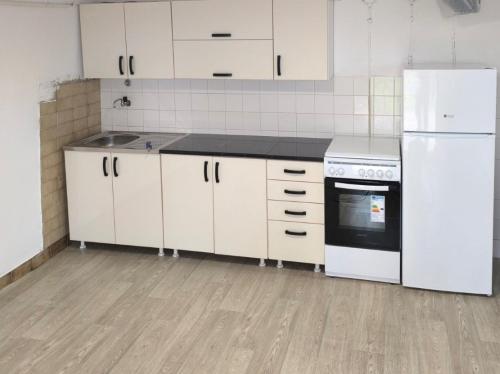 a kitchen with white cabinets and a white refrigerator at Oaza Slankamen in Slankamenački Vinogradi
