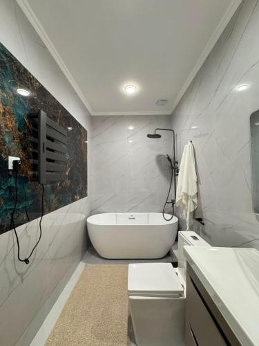 a white bathroom with a tub and a sink at K41House in Almaty