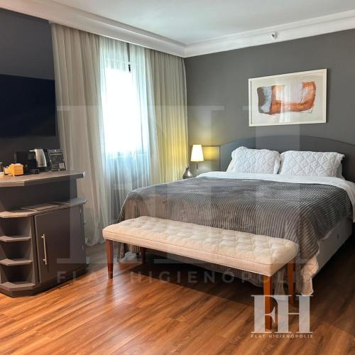 a bedroom with a bed and a bench in it at Flat Higienópolis in São Paulo