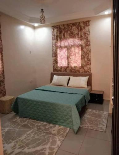 a bedroom with a bed with a green bedspread at Maisons Maktoub Djerba in Al Maqārisah