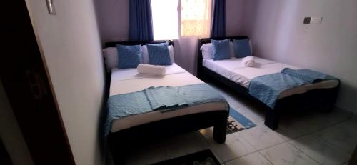 two beds in a small room with a window at Ryma Airbnbs in Mombasa