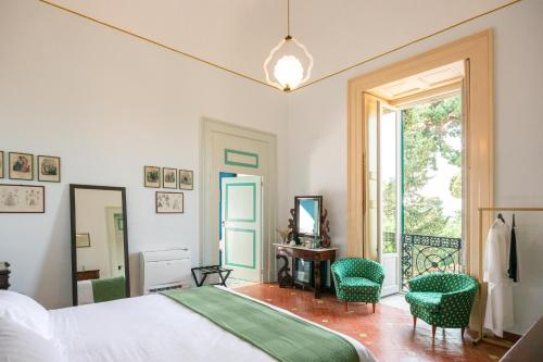 a bedroom with a bed and two chairs and a window at Villa Ceci Dimora di Storie in Andria