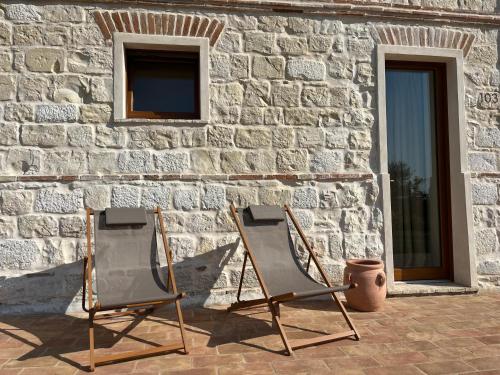 two folding chairs sitting in front of a stone wall at Pietra Museum Suites Sirolo in Sirolo