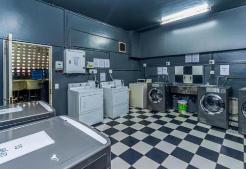 a laundry room with washing machines and a checkered floor at Mapungubwe apartment in Johannesburg