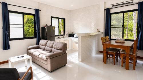 a living room with a couch and a table and a kitchen at Zen Nest in Ko Phangan