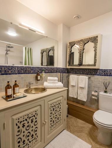 a bathroom with a sink and a toilet and mirrors at atlas golf resort in Marrakesh