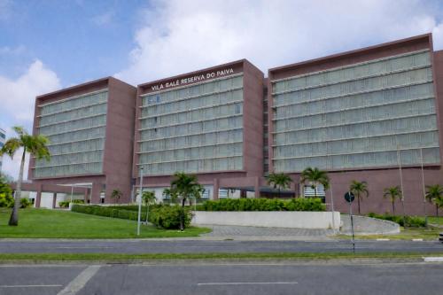 a large pink building with palm trees in front of it at Vila Gale Reserva do Paiva in Cabo de Santo Agostinho
